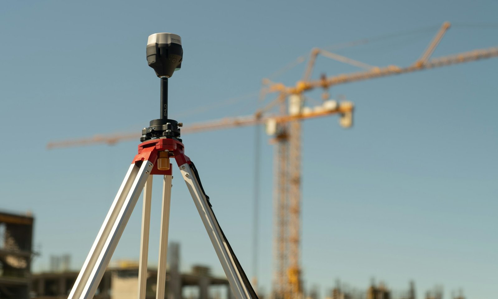 Tachymeter auf einem Stativ vor einer Baustelle